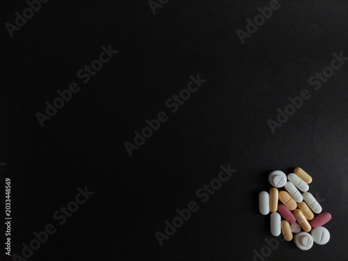 Photos Assorted pills, tablets, capsules isolated on black background with copy space for drugs, medications, prescription medicines, medical treatments, vitamins, pharmaceuticals, and healthcare concepts