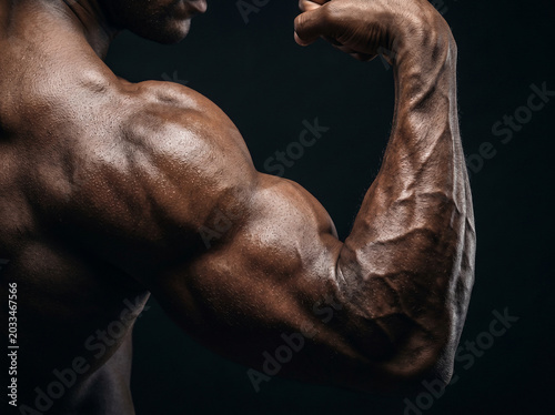 Close-up of a muscular man's bicep and shoulder flexing with prominent veins