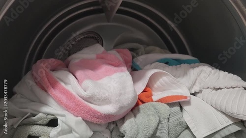 Close-up view inside a clothes dryer showing towels and fabric materials arranged in the drum during a laundry cycle.
