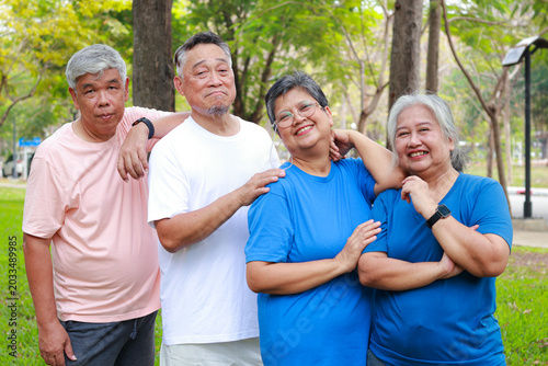 Happy group of Asian senior friends smiling and relaxing in the park, enjoying healthy active retirement lifestyle together. Concept of maintaining good health in retirement.