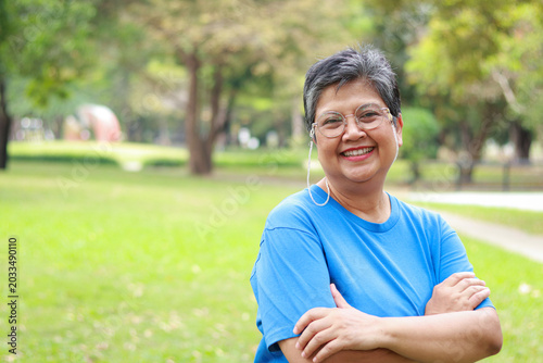 Portrait of a smiling senior Asian woman looking at camera with nature background. Exercise for good health in retirement. copy space