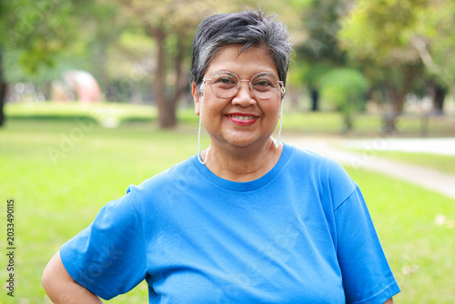 Portrait of a smiling senior Asian woman looking at camera with nature background. Exercise for good health in retirement.