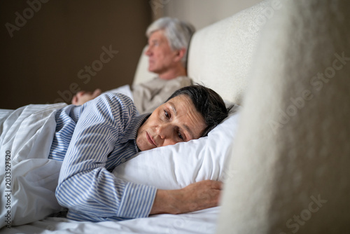 Fotografia Upset offended elderly wife avoiding contact with husband while lying together in bed in bedroom after quarrel, senior married couple in mental confrontation, aged partners relationships psychology