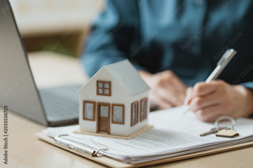 Obraz premium Real estate mortgage and property purchase concept with house model, contract documents, and key symbolizing home ownership, financing, and legal agreement.