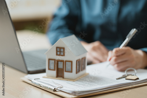 Real estate mortgage and property purchase concept with house model, contract documents, and key symbolizing home ownership, financing, and legal agreement.