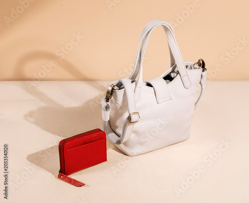 White leather bag and red wallet set against a brown background, perfect for a leather product catalog design