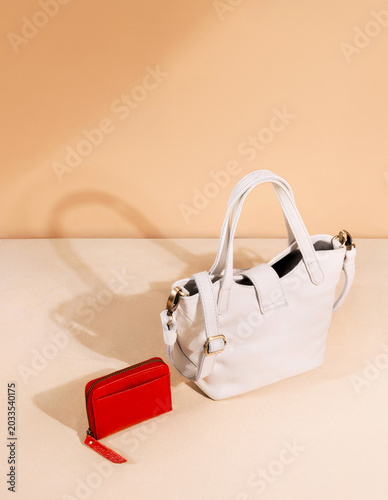White leather bag and red wallet set against a brown background, perfect for a leather product catalog design