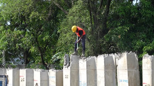 A contractor focuses on workers at the construction site using light and heavy equipment in a building under construction