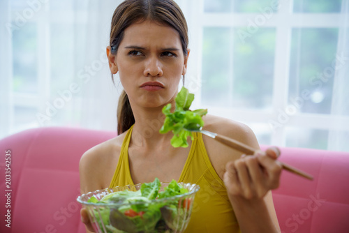 Bild auf Leinwand Woman salad lettuce bowl fork frown reluctant healthy eating home