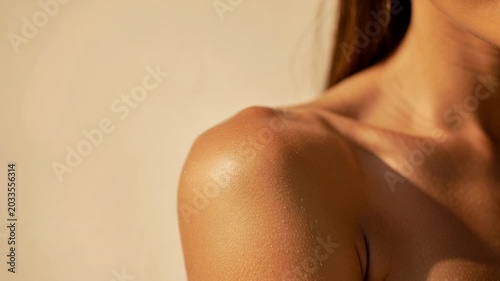 Close up of female shoulder with smooth sun-kissed skin and natural texture under warm light