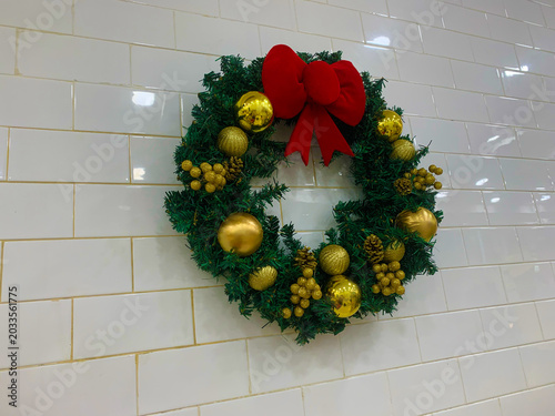 Konstfotografi Christmas wreath with red ribbon hang on a white walls
