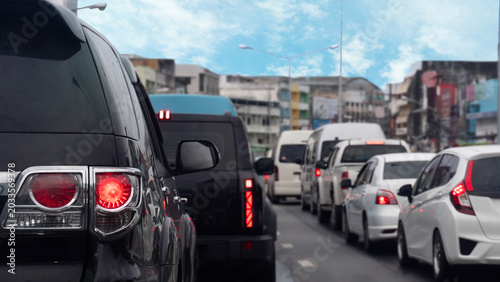 Tight rear view of black vehicle stopped on the asphalt road. City traffic during the day. Long queue of diverse many cars stretches ahead down a congested urban lane. Traffic congestion in Thailand.