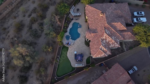 An aerial view of desert landscaped backyard in Arizona featuring a Travertine tiled pool deck, spa, out door chitchat and fireplace. 