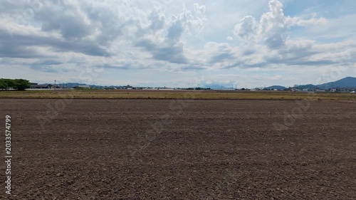 Side tracking shot of an empty unplanted rice field in spring