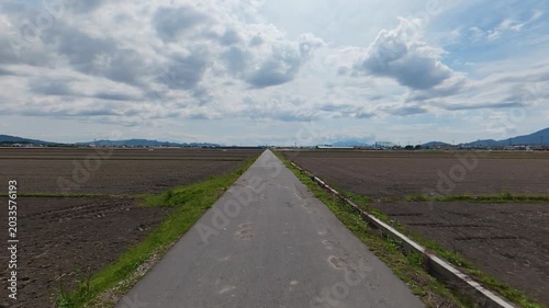POV shot of moving forward on a single road between empty unplanted rice fields