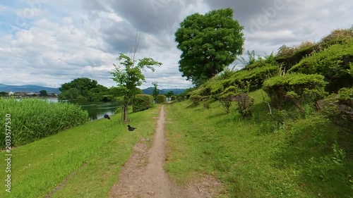 Slow motion POV shot of moving along a narrow path beside a calm lake