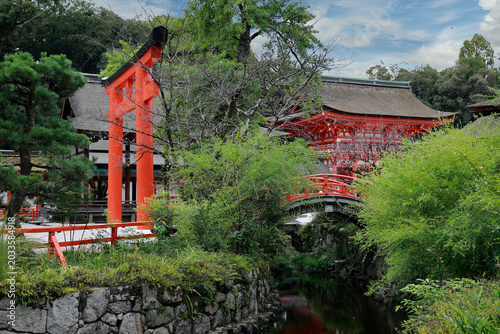 Red torii gate and arched bridge with stream at Kamigamo Shinto shrine, Kyoto, Japan