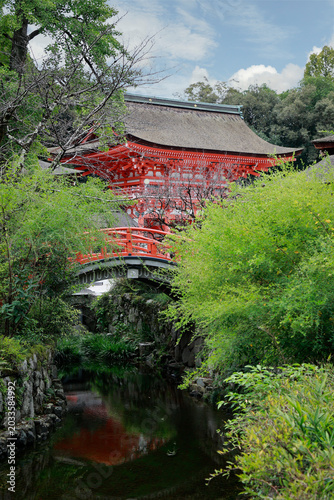 Red Japanese bridge over stream with pagoda at Kamigamo Shinto shrine, Kyoto, Japan