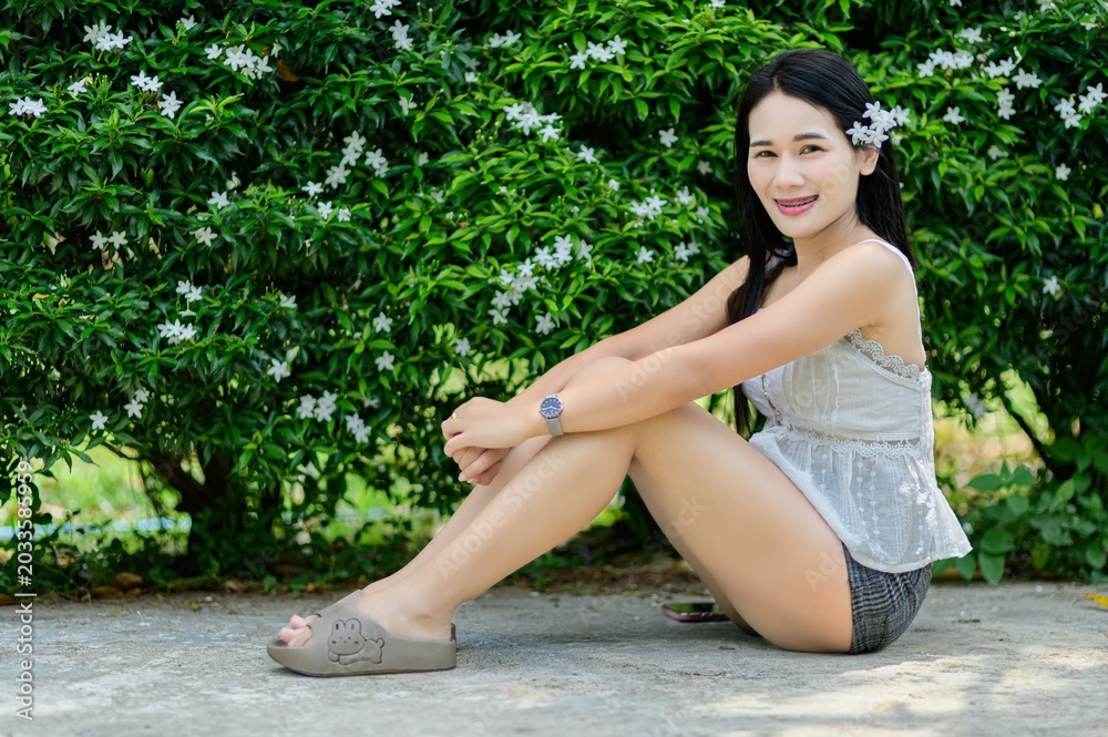 Naklejka premium Young Woman Sitting Among Flowers in Outdoor Nature Setting