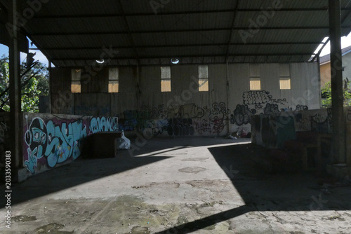 Φωτογραφία Abandoned Warehouse Interior with Colorful Graffiti and Natural Light Streaming