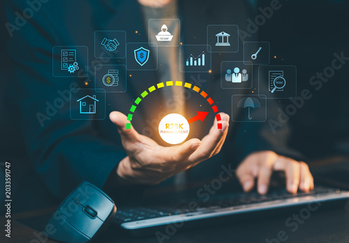 Risk management and financial crisis assessment concept. Businessman presenting risk gauge indicator with security, scam, insurance, and banking icons on virtual screen.