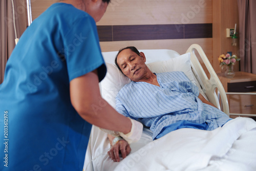 A nurse is taking care of an elderly patient in a hospital.