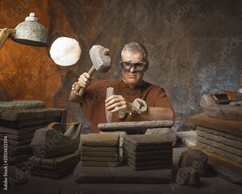 Konstfotografi Frustrated office worker caveman hand carving inscriptions on a stone tablet