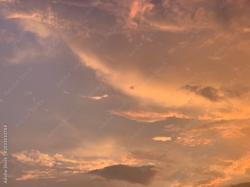 Naklejka premium Cinematic orange sunset clouds with dramatic pastel sky and soft texture, captured in wide-angle focus. Perfect for luxury branding, wellness ads, travel banners and aesthetic wallpapers.