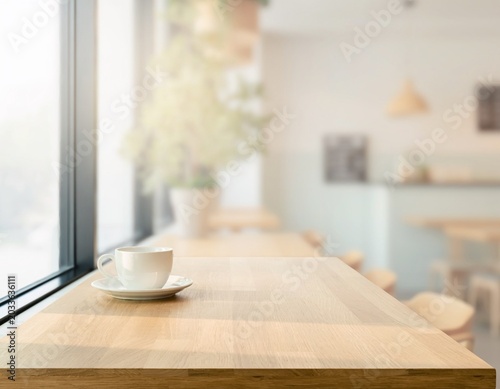 A serene coffee cup sits on a polished wooden table in a brightly lit cafe by a large window, evoking a sense of calm and relaxation