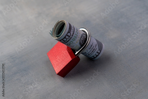 Fotografie A roll of hundred-dollar bills secured tightly inside a red padlock