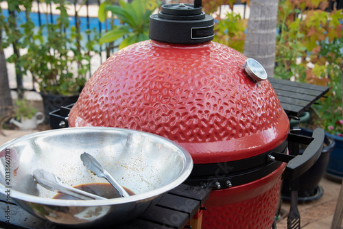 Fotografía Red ceramic grill cooking outdoors in a backyard setting