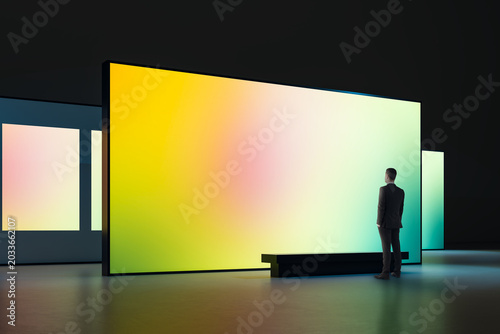 Canvastavla Large illuminated gradient display in modern gallery with a man observing the vibrant screen in a dark interior exhibition space showcasing digital art