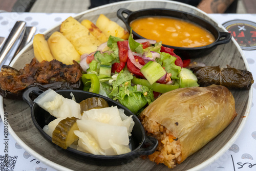 A diverse and colorful traditional vegan Albanian meal featuring an array of local dishes. Includes stuffed peppers, potatoes, bean stew, dolma, and a fresh salad, served in Shkoder, Albania.