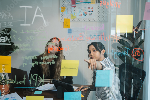 Colleagues Brainstorming Ideas with Sticky Notes on Glass Board