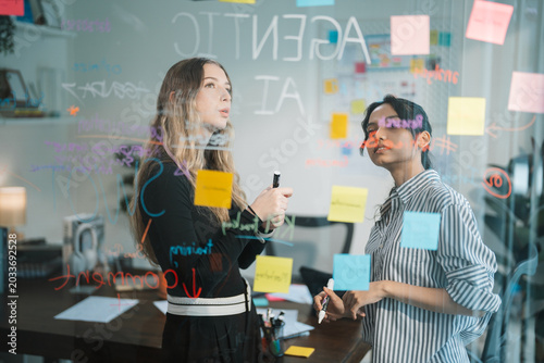 Obraz na płótnie Colleagues Brainstorming Ideas with Sticky Notes on Glass Board