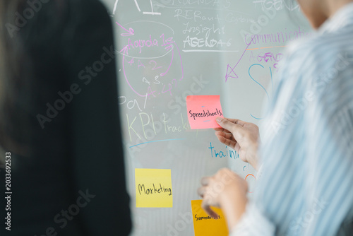 Colleagues Brainstorming Ideas with Sticky Notes on Glass Board