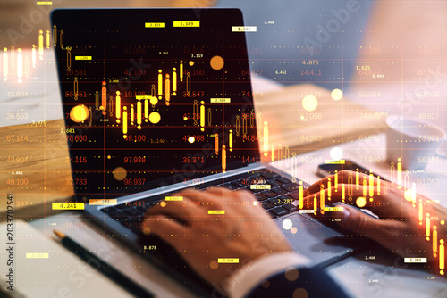 Foto Business trader working on laptop with glowing financial charts and digital market indicators overlaid on office desk background in abstract style