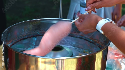 Preparing Fluffy Pink Cotton Candy At Outdoor Fair showing the process of shaping a sweet dessert from sugar strands during a festive outdoor event