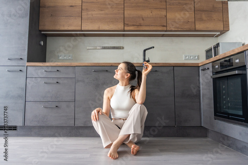 Tableau sur toile Young woman sitting on kitchen floor in new apartment and holding house keys
