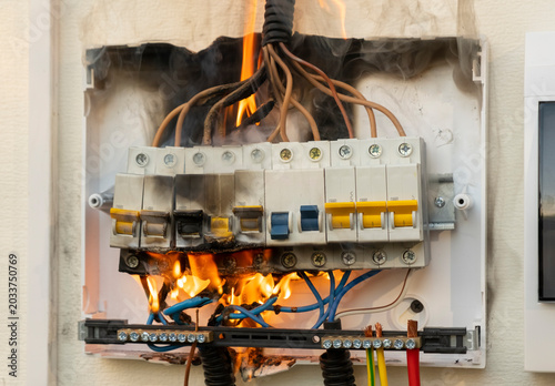 Electrical panel on fire in a home during the day causing smoke and damage to wires and circuitry