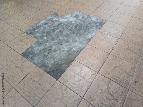 фотографія A top-down view of a domestic tiled floor showing a section of replaced or repaired rectangular ceramic tiles with a different color and texture pattern