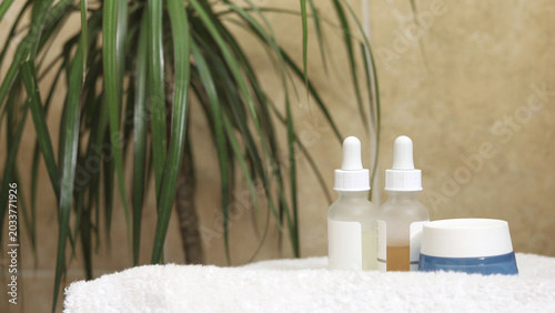 Natural Spa Skincare Set. Jars of cream and serums stand on a white terry soft towel in the bathroom.