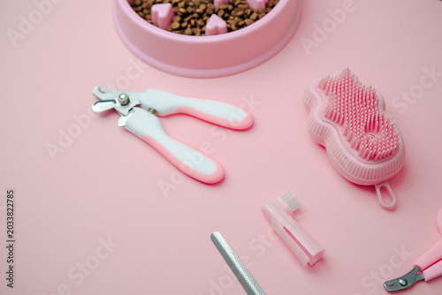 Foto Pet grooming tools include nail clippers, brushes, and teeth cleaner on pink background