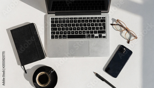 Overhead view of laptop notebook and mobile phone on a white surface