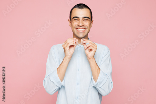 Fotografie Young toothy smiling happy excited middle eastern man wear blue shirt point index fingers on opened mouth teeth isolated on plain pastel light pink wall background studio portrait