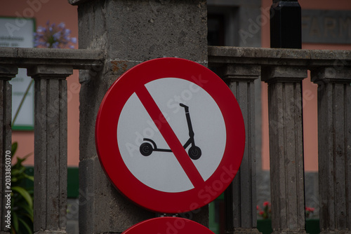 Electric scooter prohibited sign mounted on metal fence in urban area
