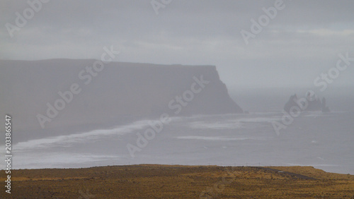 Fotografie Paysage côtier islandais avec falaise au loin