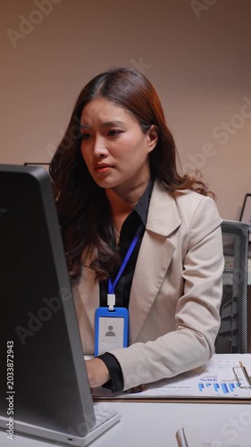 Tired asian businesswoman working overtime and stretching at her desk