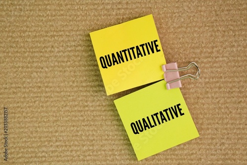 Paper and clip with two words QUANTITATIVE and QUALITATIVE. Research is typically divided. Quantitative data deals with numbers and statistics, Qualitative data deals with words, meanings