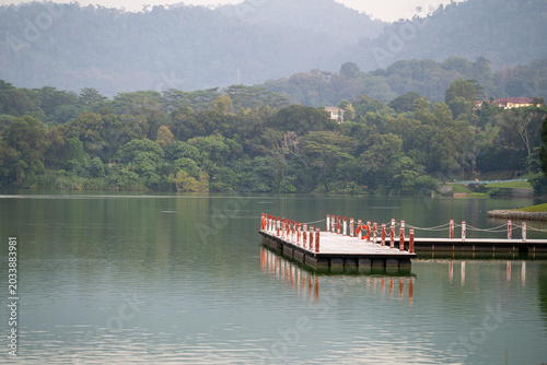 Floating jetty on a tranquil lake with forested hills in the background.